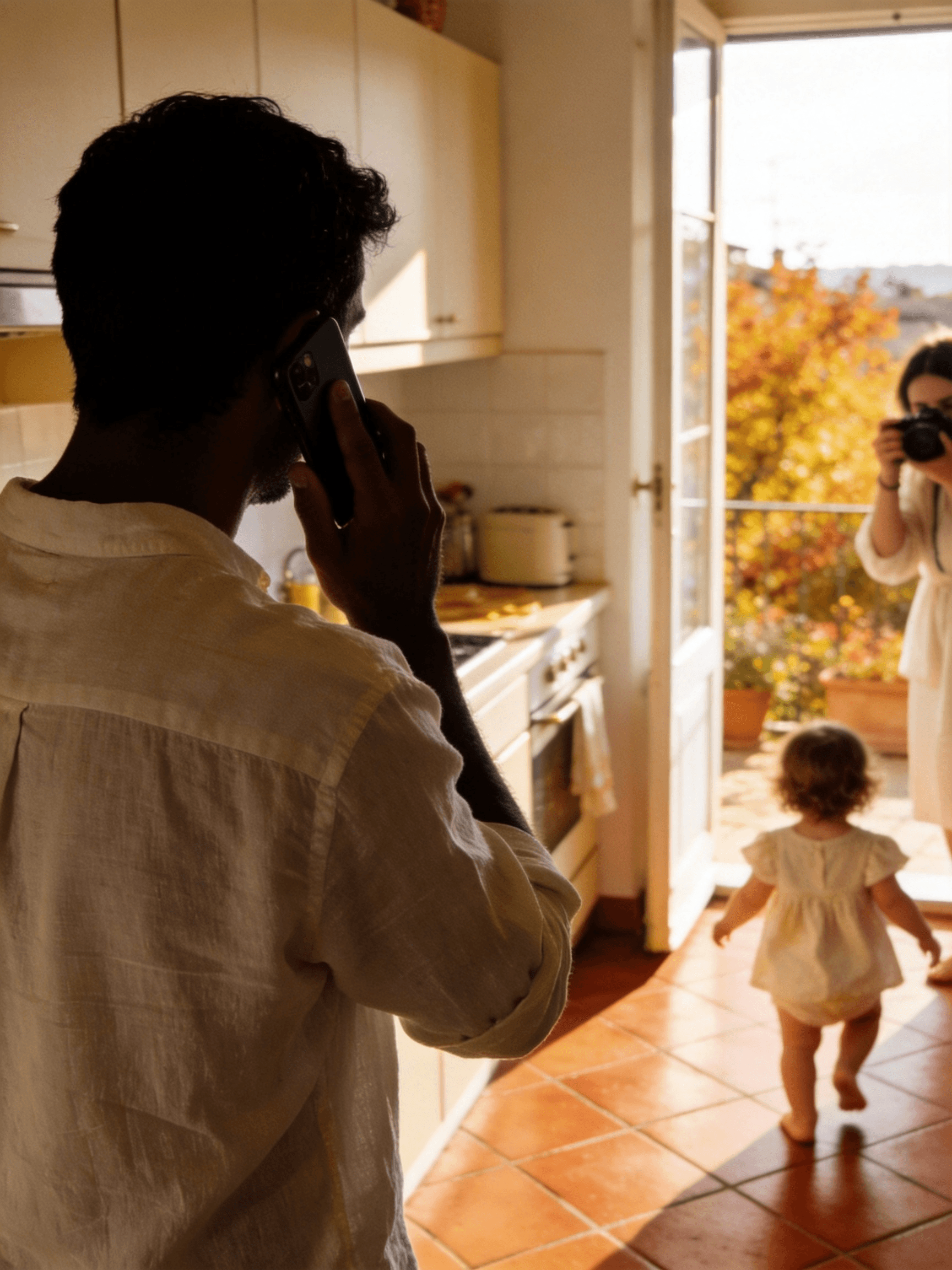 A golden-hour Italian kitchen — a father on the phone with his back turned